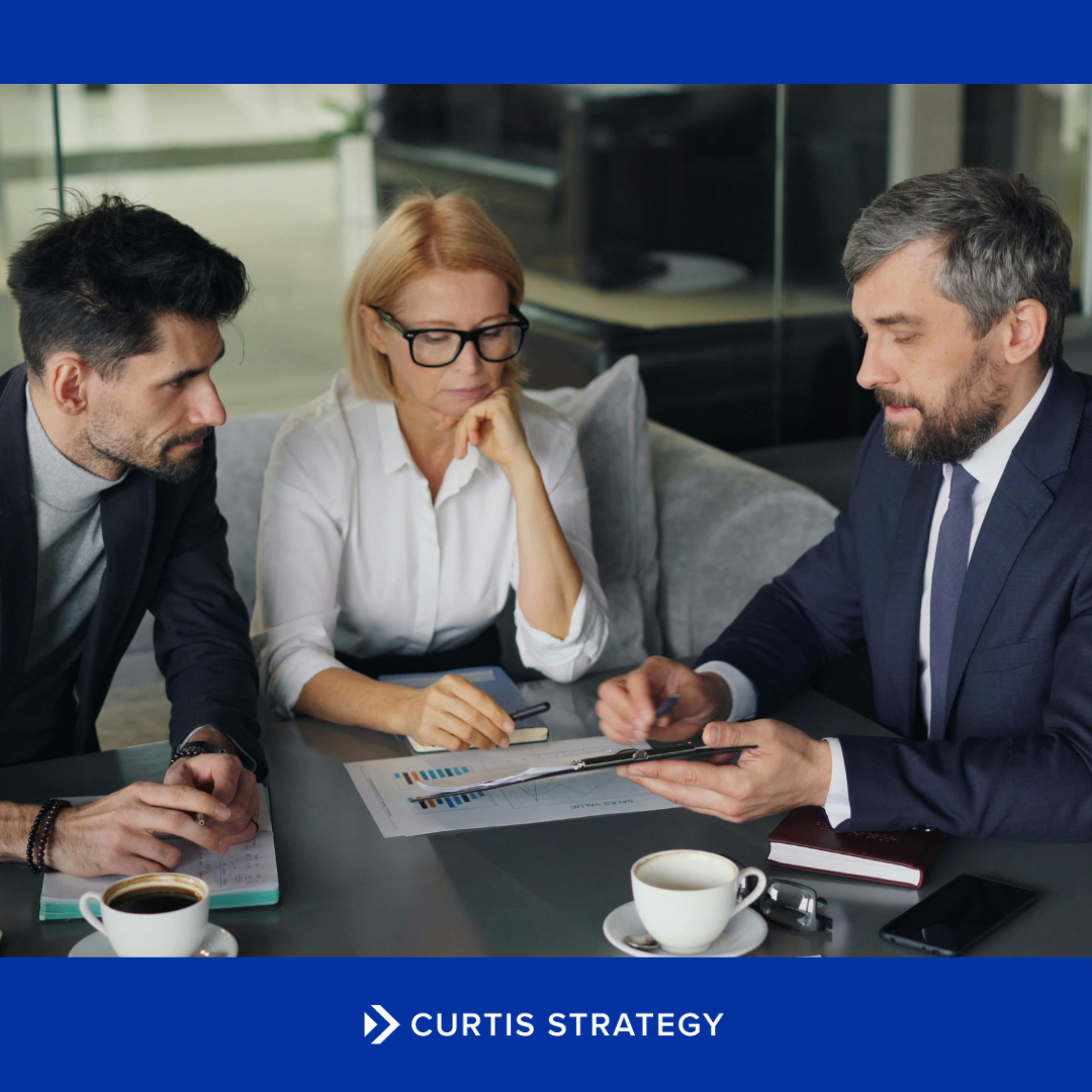 Executive team discussing strategy around a conference table during a nonprofit merger.