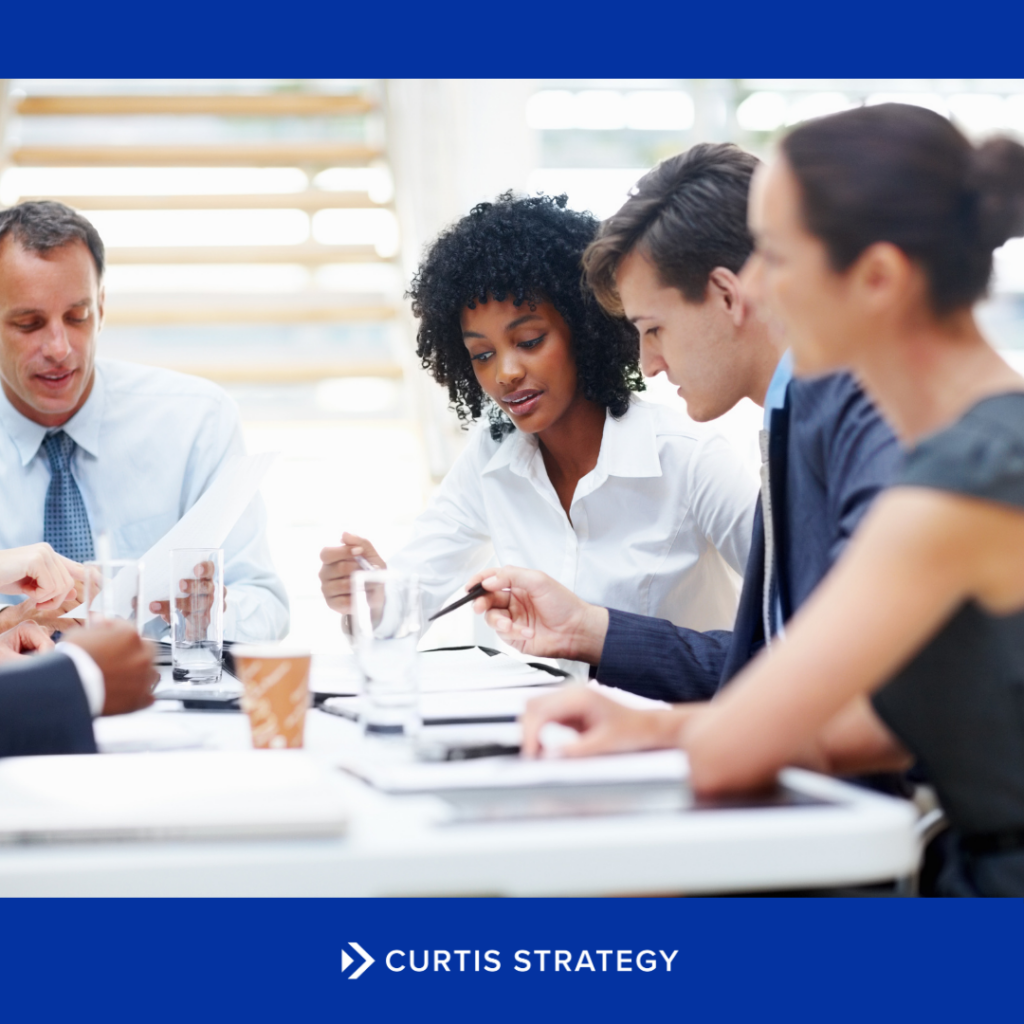 Nonprofit board members engaged in a board governance meeting around a conference table.