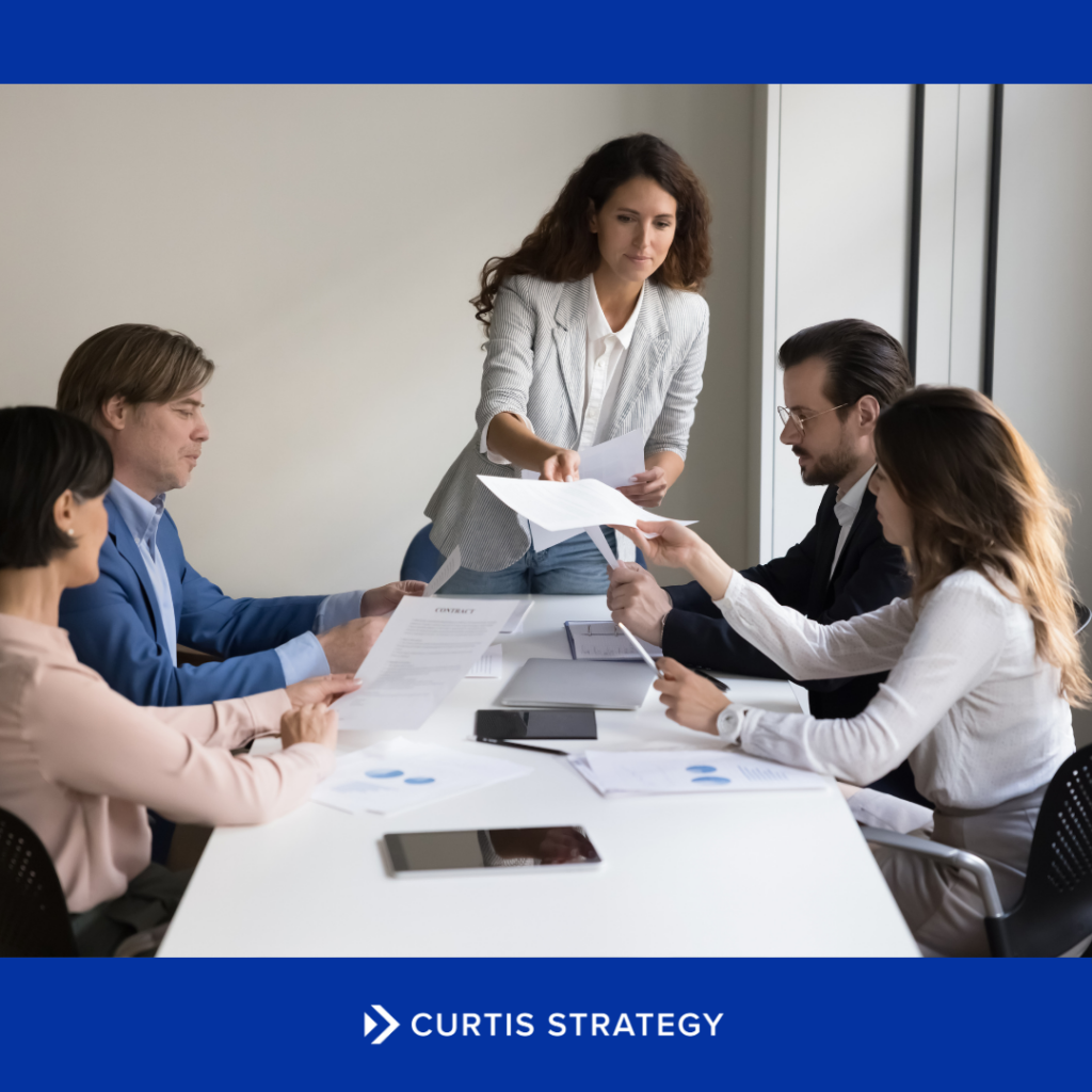 Executives reviewing strategic partnership documents around a table during a health and human services merger.